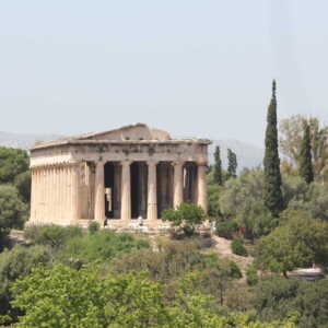 Ancient Greek temple surrounded by greenery under a clear sky.