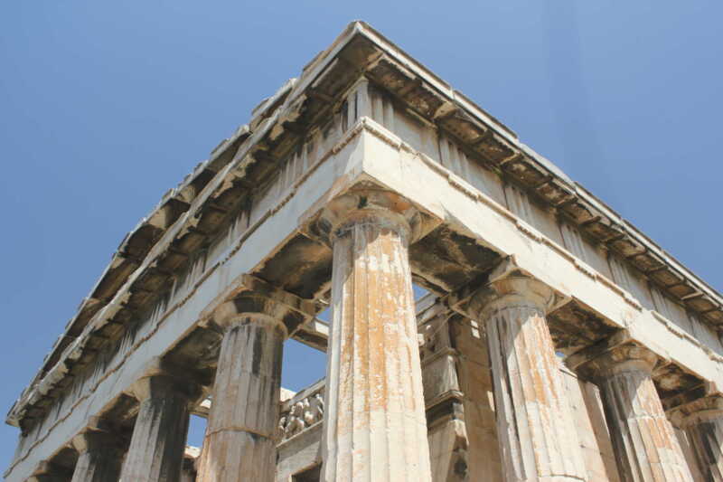 Ancient Greek temple columns under a clear blue sky.